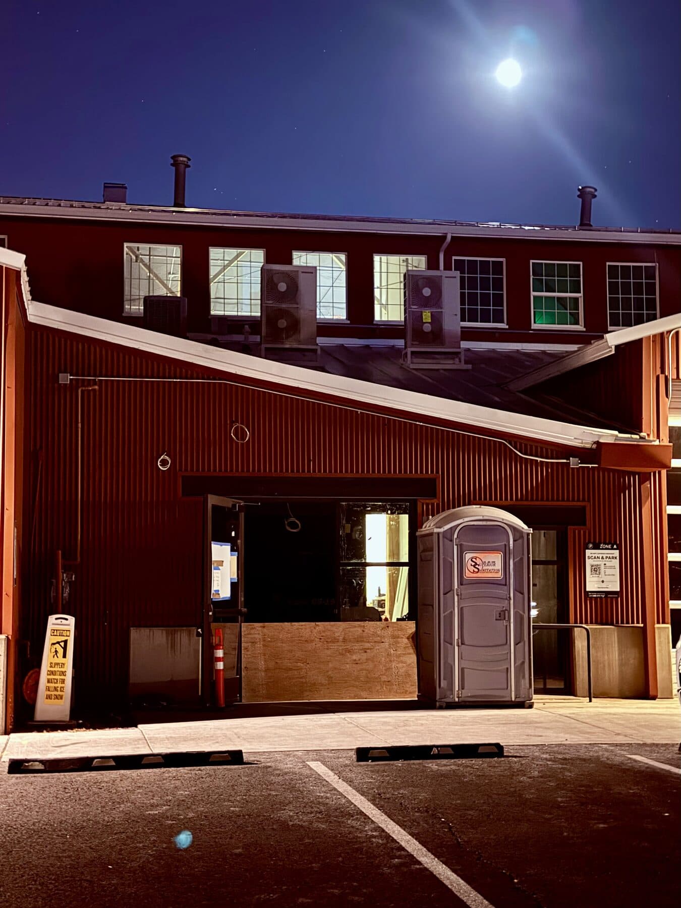 The Box Factory at night, the bay door open under a full moon