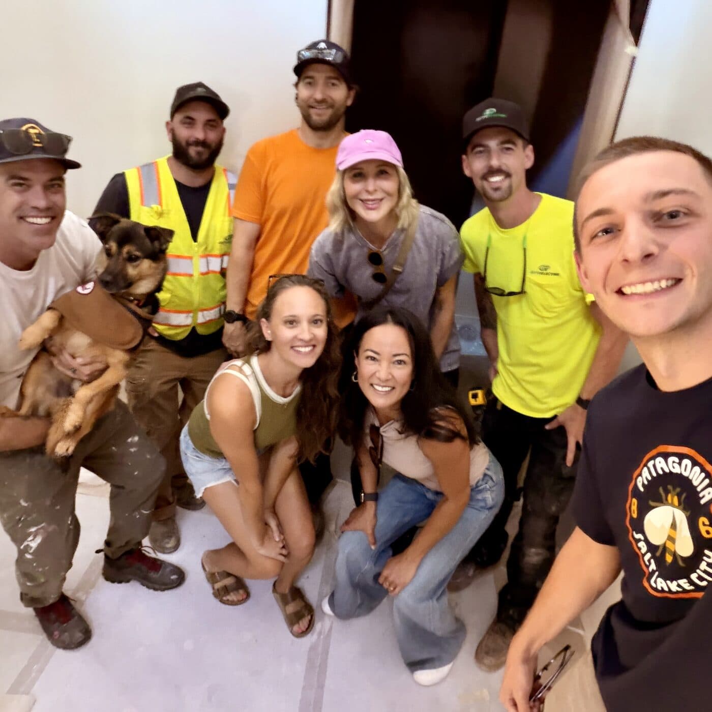 A crowd of people and a dog packed into the unfinished space
